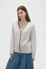 Cardigan de viscosa color marrón, con cuello en V, cierre frontal con botones y detalle de costura decorativa en contraste a lo largo de los bordes.
