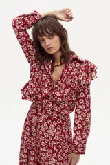 Camisa de manga larga con estampado floral, confeccionada en lino. Presenta volados dobles en el frente y la espalda que se extienden en diagonal desde los hombros hasta la cintura, cuello clásico y cierre frontal con botones a tono.