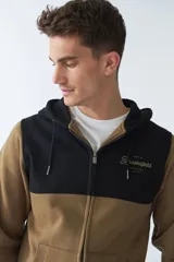 Campera de felpa gris con capucha y cordón ajustable, cierre frontal con cremallera, bolsillos laterales, mangas largas y logo estampado en el pecho.