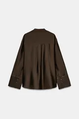 Camisa ZW Collection de color marrón oscuro, con cuello mao, manga larga con puños anchos y cierre frontal oculto por solapa. Cuenta con un bolsillo de parche en el pecho adornado con bordados a tono, los cuales también se repiten en los puños.