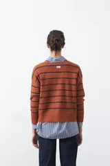 Sweater de tejido de punto con diseño de rayas horizontales en tonos bordó y rojo. Presenta cuello redondo, mangas largas con hombros caídos y terminaciones acanaladas en puños, cuello y ruedo.