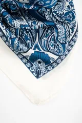 Bandana cuadrada de color blanco con diseño ornamental en tonos de azul, con estampado paisley y detalles geométricos.
