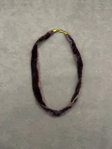 Gargantilla tipo choker confeccionada en cinta de terciopelo color violeta oscuro, con bordes deshilachados y terminales metálicos dorados con cierre de mosquetón.