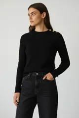 Sweater de tejido acanalado en color negro, con cuello redondo y detalle de botones dorados sobre el hombro izquierdo. De manga larga y ajuste al cuerpo.