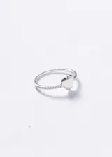 Anillo de plata 925 con diseño de corazón liso central y banda decorada con pequeñas zirconias incrustadas en los laterales.