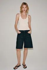 Bermuda de denim color bordó, de tiro medio y corte relaxed, con diseño de cinco bolsillos, trabillas para cinto y bajo desflecado.