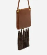 Bolso tipo postman de tamaño mediano en color marrón, con cierre superior y correa ajustable. Presenta un diseño rectangular con múltiples borlas largas en la parte inferior con estampado animal print.
