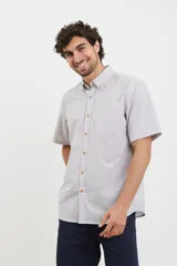 Camisa de manga corta a rayas verticales color celeste y blanco, con cuello abotonado y bolsillo en el pecho.