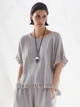 Blusa gris de lino con mangas cortas y volados en ruedo y mangas.