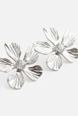 Aros con diseño de flor de metal plateado con textura y un cristal transparente en el centro.