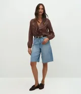 Bermuda estilo jorts de cintura alta, confeccionada en denim de algodón con lavado clásico, trabillas para cinturón, cierre frontal con botones y bolsillos funcionales.