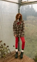 Blazer sastrero de corte oversize, con cuello solapa, manga larga y cierre frontal con botones. Presenta un diseño a cuadros en tonos bordó y blanco, con detalles de costuras bordadas en hilo amarillo en los bolsillos y el ruedo. Incluye forro interior de satén.