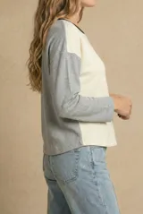 Sweater de tejido de punto con diseño bicolor, cuerpo en color crema y mangas en gris melange, con cuello redondo en contraste negro.