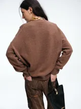 Sweater de tejido de punto en color rosa claro con motas de colores, de corte holgado, cuello redondo y mangas largas con hombros caídos.