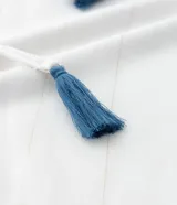 Blusa color blanco con escote en pico con bordado de corazones azules, mangas largas con puños elásticos, lazos con borlas y detalle de hilo metalizado.