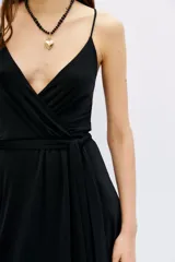 Vestido corto negro ajustado al cuerpo, con escote cruzado en V, breteles finos y lazo ajustable en la cintura.