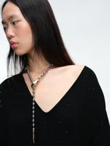 Sweater de punto gris con escote en V profundo, hombros caídos y mangas largas. Presenta un diseño de calce relajado con sutiles micro lentejuelas integradas en el tejido.