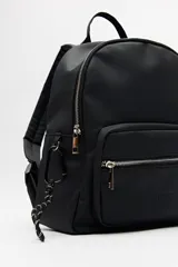 Mochila negra de símil cuero con acabado mate, diseño minimalista y bolsillo frontal con cierre metálico.