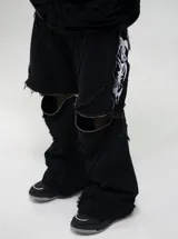 Pantalón de jean estilo baggy fit, color negro, con diseño de costuras visibles y cierres laterales que permiten convertirlo en bermuda. Presenta estampado serigráfico en los laterales.