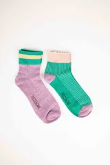 Medias de media caña a rayas brillantes, una de color lila con franjas verde y amarillo en el borde superior, y otra de color verde con rayas blancas y borde superior rosa.