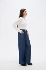 Pantalon de lyocell azul oscuro, de corte wide leg y tiro alto. Presenta cintura estilo paper bag con lazo ajustable del mismo tejido y cierre frontal con botón.
