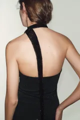 Top palabra de honor negro con brillo, confeccionado en tejido elástico y con aplicación de hilo metalizado.