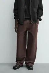 Pantalón jogger de algodón color marrón oscuro, de corte relajado y pierna ancha. Presenta cintura elástica con cordón ajustable y bolsillos laterales y uno trasero de plastrón.
