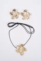 Set compuesto por un collar con cordón negro y dije de flor dorada con perla central, y un par de aros tipo clip con el mismo diseño de flor dorada y perla.