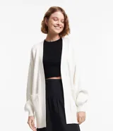 Cardigan alargado color blanco, confeccionado en tejido de punto pesado, con bolsillos laterales y mangas largas.