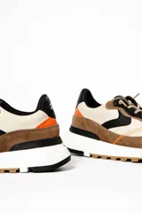 Zapatillas deportivas marrones y beige con detalles en negro y naranja.