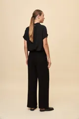 Pantalón negro de pierna ancha y calce fluido, con pinzas delanteras y bolsillos laterales.