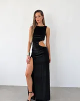Vestido largo de terciopelo negro, sin mangas, con escote redondo, abertura lateral en la pierna y detalles de recortes cut-out en la cintura.