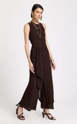 Pantalón de punto color chocolate, de corte recto y tiro alto. Presenta una superposición frontal cruzada con lazo lateral en la cintura, textura tejida con ligera transparencia en el dobladillo y detalle de ribete de encaje en la parte inferior.