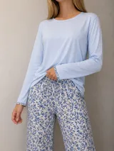 Pijama compuesto por una remera de manga larga color celeste con detalles estampados en los puños y un pantalón largo con estampado floral en tonos azules y celestes, con cintura elástica.