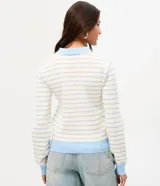 Blusa de punto a rayas horizontales celestes y blancas, con cuello polo celeste, cierre frontal con botones, bolsillo aplicado en el pecho y mangas largas.