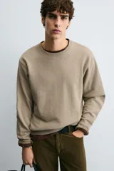 Sudadera de cuello redondo con ajuste regular, confeccionada en tejido de mezcla de algodón con interior de rizo y acabados en rib en cuello, puños y ruedo.