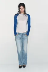 Camiseta de manga larga con cuerpo blanco y mangas raglán azules. Tiene cuello redondo y corte slim fit.