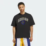 Remera negra de algodón con ajuste holgado, cuello redondo y mangas cortas. Presenta un estampado gráfico frontal con la palabra "ADIDAS" en estilo universitario con borde amarillo y azul, acompañado de un emblema circular en el centro.