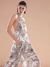 Vestido largo blanco con estampado floral en tonos marrones. Tiene cuello halter y corte holgado.