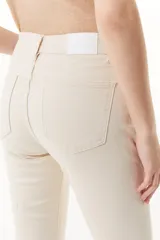 Jean color crudo de tiro medio/alto, silueta levemente acampanada desde la rodilla y tajo en el frente de la pierna.