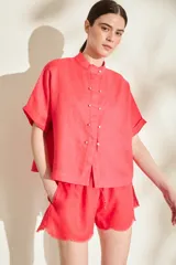 Blusa de lino color rojo coral, con silueta amplia, cuello mao y cartera frontal con botones dorados.