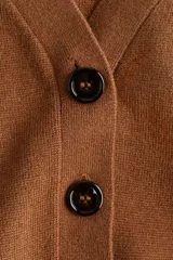 Cárdigan de punto color marrón, con cuello en V y cierre frontal de cuatro botones oscuros. Presenta un calce holgado y mangas largas.