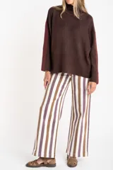 Sweater de punto con cuello alto, diseño oversize y mangas largas. Presenta un contraste de color en el cuello y una franja vertical en las mangas en tono beige.