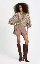 Blusa de punto con rayas verticales en tonos marrón, beige, verde y blanco, corte amplio, escote redondo y mangas largas anchas con puños ajustados.