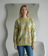 Sweater de punto color verde con diseño de rombos decorados con lentejuelas plateadas y doradas. Presenta cuello redondo, mangas largas y puños y ruedo acanalados.