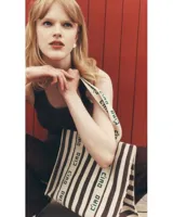 Bolso tote de lona a rayas verticales marrones y blancas con asas de mano y estampado "Ciao" en las asas.