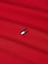 Chomba roja de Tommy Hilfiger de corte regular, confeccionada en algodón. Tiene cuello tipo polo, tapeta de dos botones y logo bordado en el pecho.