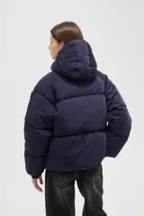 Campera puffer de color marrón oscuro, con diseño capitoneado, cierre frontal, capucha ajustable y bolsillos laterales con cierre.