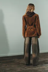 Blazer de gamuza color marrón con cuello solapa, manga larga con hombreras y cierre frontal con botones. Incluye bolsillos con solapa en el delantero, bolsillo de vivo en el pecho y cinturón de lazada en el mismo material.