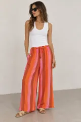 Pantalón de tiro alto y pierna ancha con estampado de rayas verticales en tonos rosados, naranjas y marrones. Cuenta con cintura elástica con cordón de ajuste y bolsillos laterales.